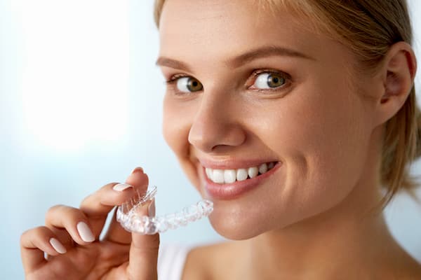 אישה מחייכת מחזיקה סד ליישור שיניים